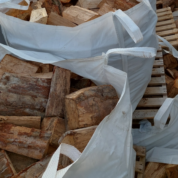 multiple jumbo 300kg bags of kiln dried hardwood firewood logs stacked on top of each other